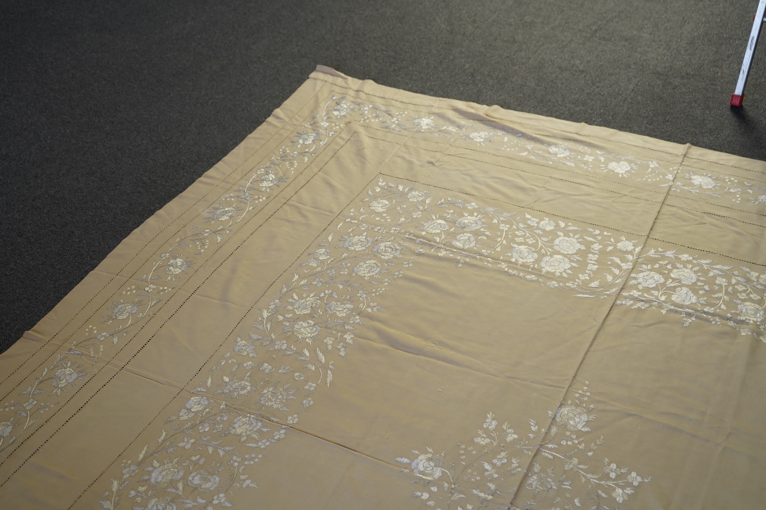 A 1920’s heavy shantung silk hand embroidered table cover. Worked with decorative rows of button hole stitch. Embroidered with white, green and blue silk flowers. 240cm x 204cm. Condition - some fine holes near corners,